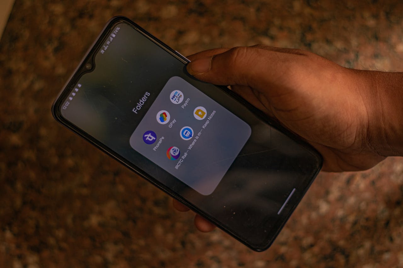 hero-img-02 A hand holds a smartphone displaying popular payment apps for digital transactions.