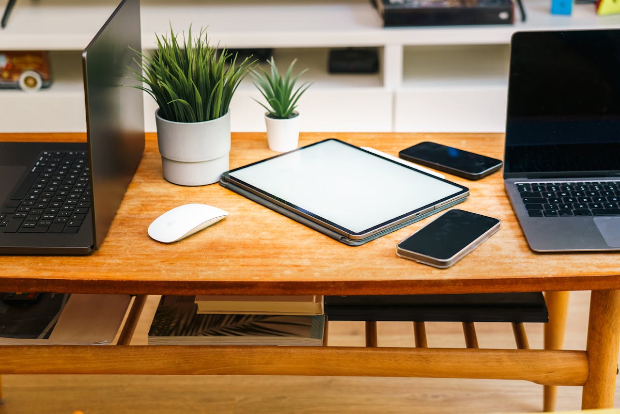 hero-img-01 A stylish home office desk with laptops, tablet, smartphones, and potted plants.